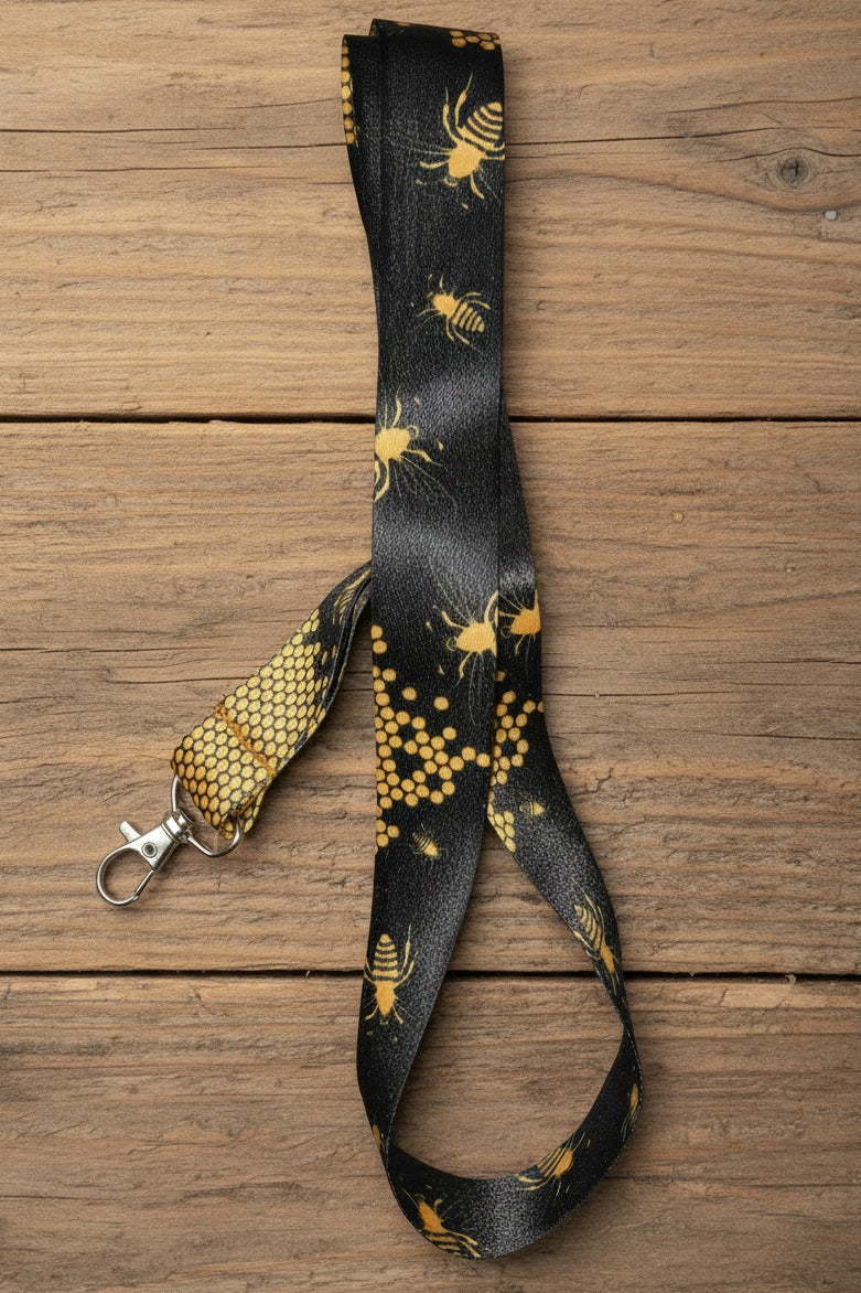 Black lanyard with yellowish gold bees and honeycomb pattern