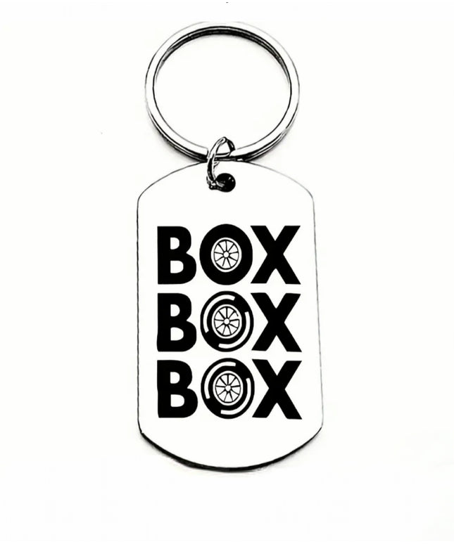 Silver keychain that reads Box Box Box with car tires for the letter O