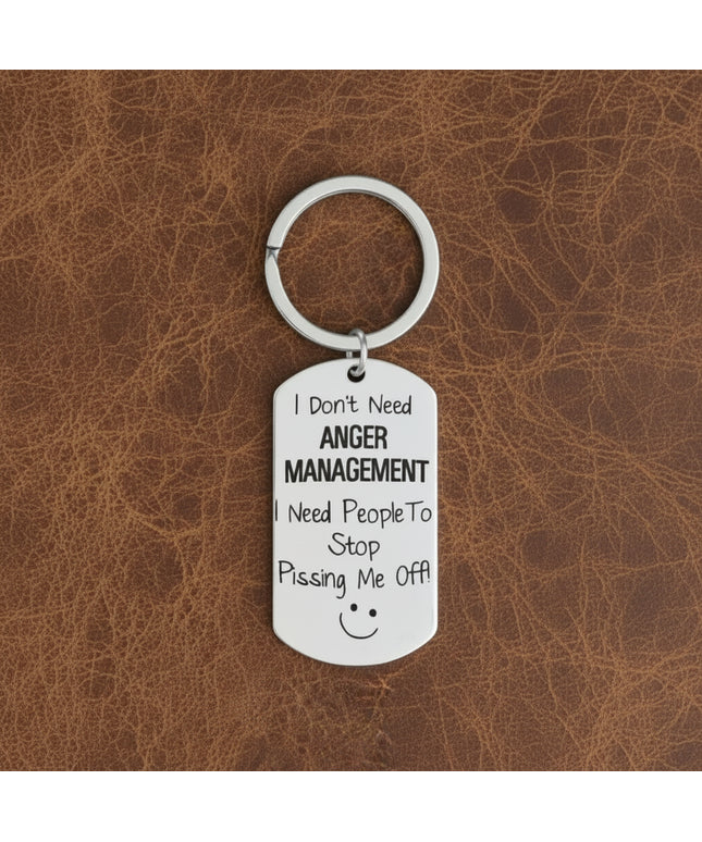 Keychain with humorous text on a gray surface with plants