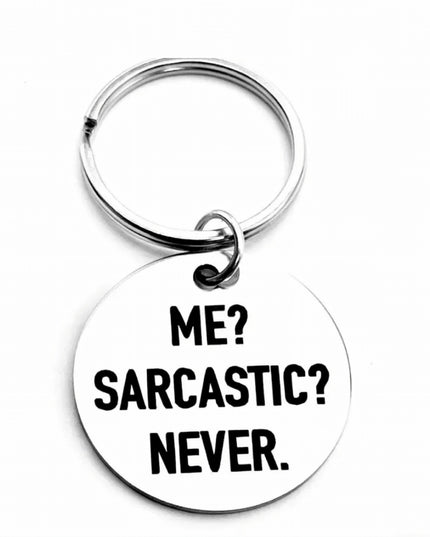 Silver keychain with round charm etched with words Me? Sarcastic? Never. in black font