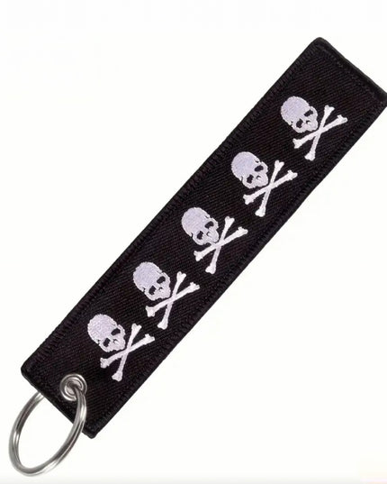 Black embroidered keychain tag with white skulls and crossbones
