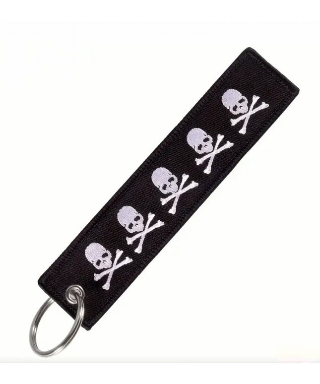 Black embroidered keychain tag with white skulls and crossbones