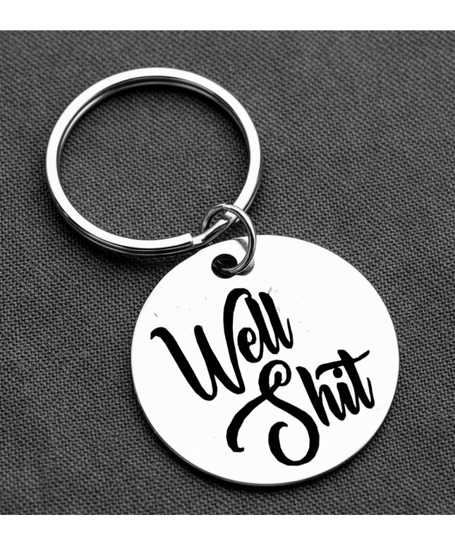 Keychain with 'Well Shit' text on a gray background