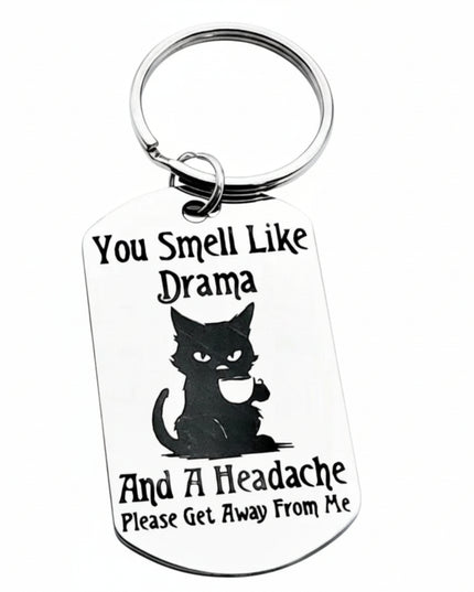 Keychain with a black cat illustration and humorous text on a white background